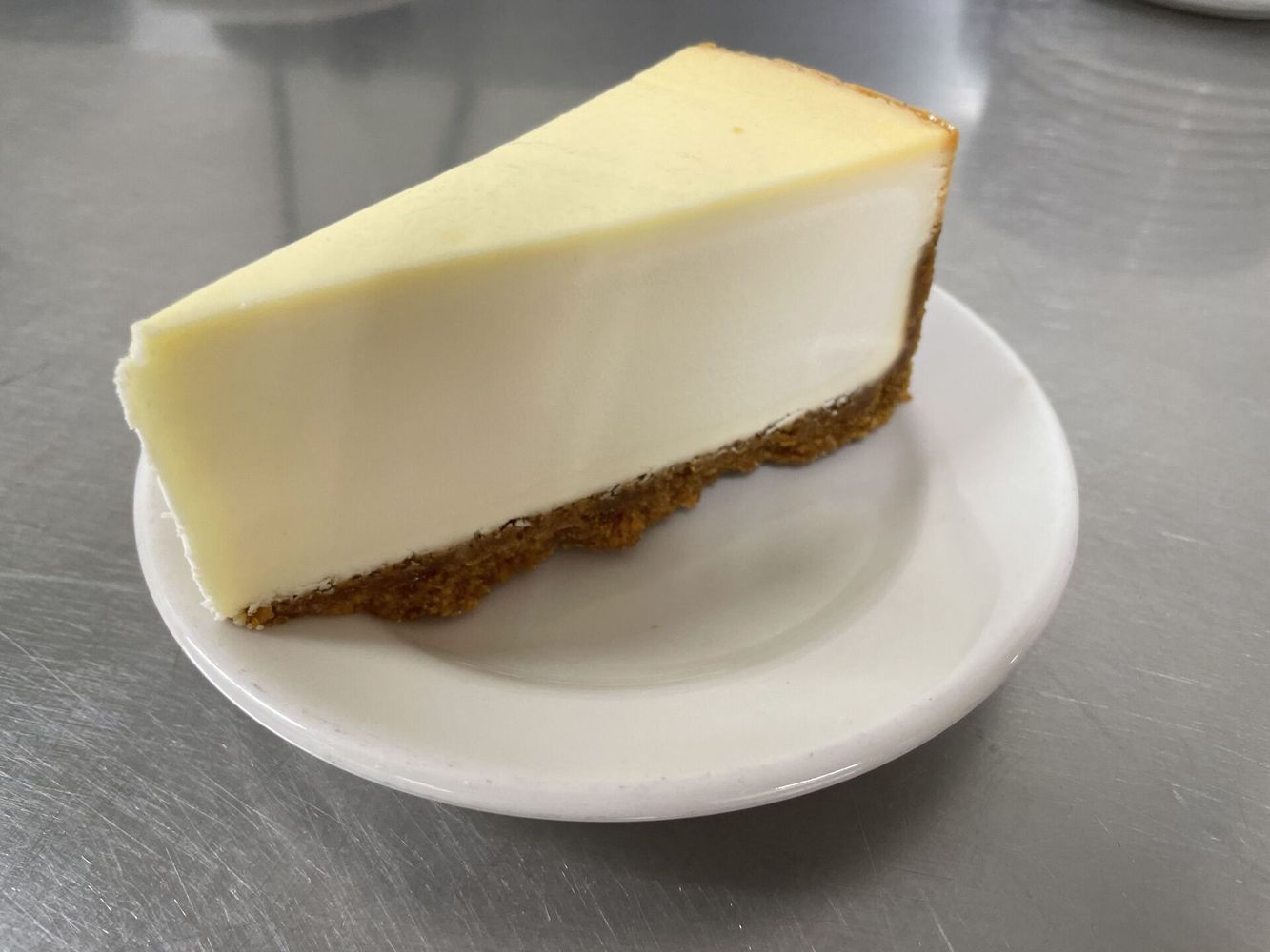 A slice of cheesecake is on a small white plate.