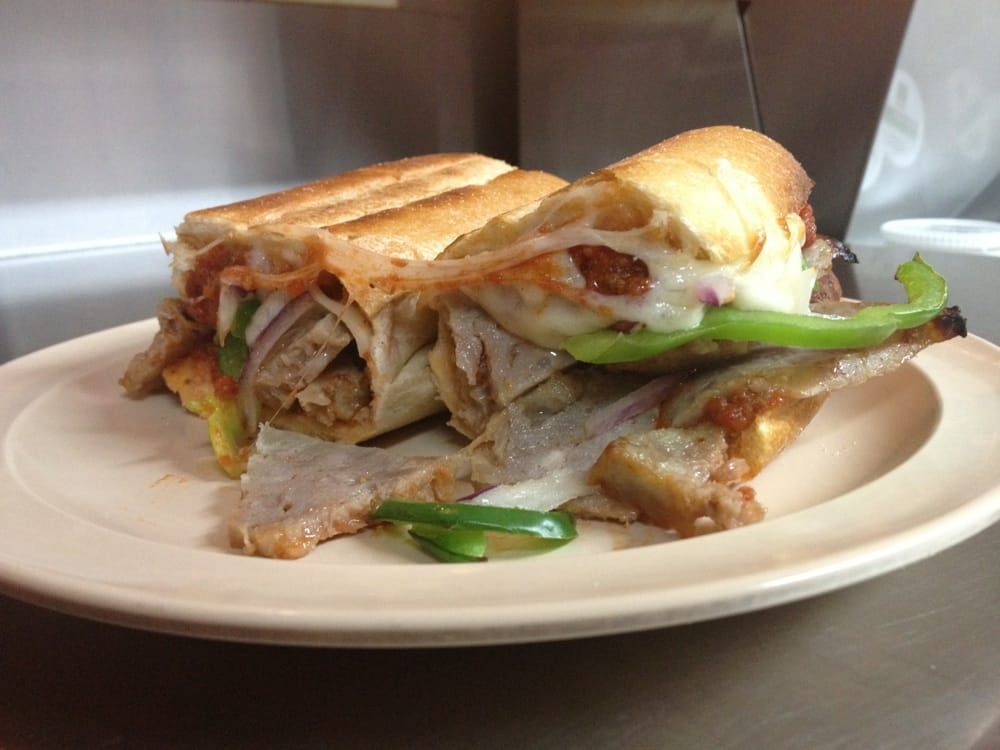 A sandwich with meat and vegetables on a white plate.