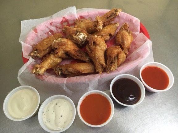 A basket of chicken wings surrounded by dipping sauces.