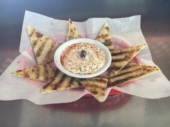 A basket of grilled pita bread and a bowl of dip.