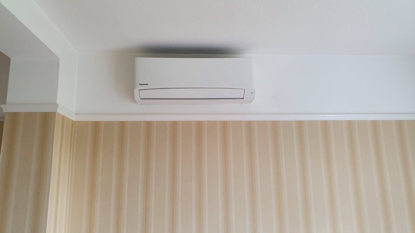 A wall mounted AC unit above some tongue and groove.