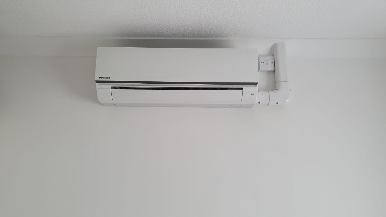 A white, wall-mounted AC unit - front view.