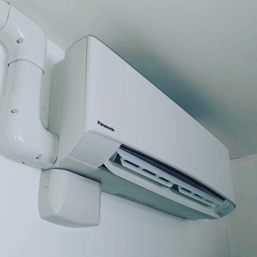 A white, wall-mounted AC unit - side view.