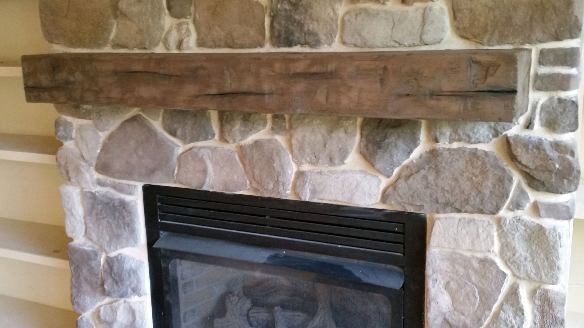 a stone fireplace with a wooden mantle in a log cabin.