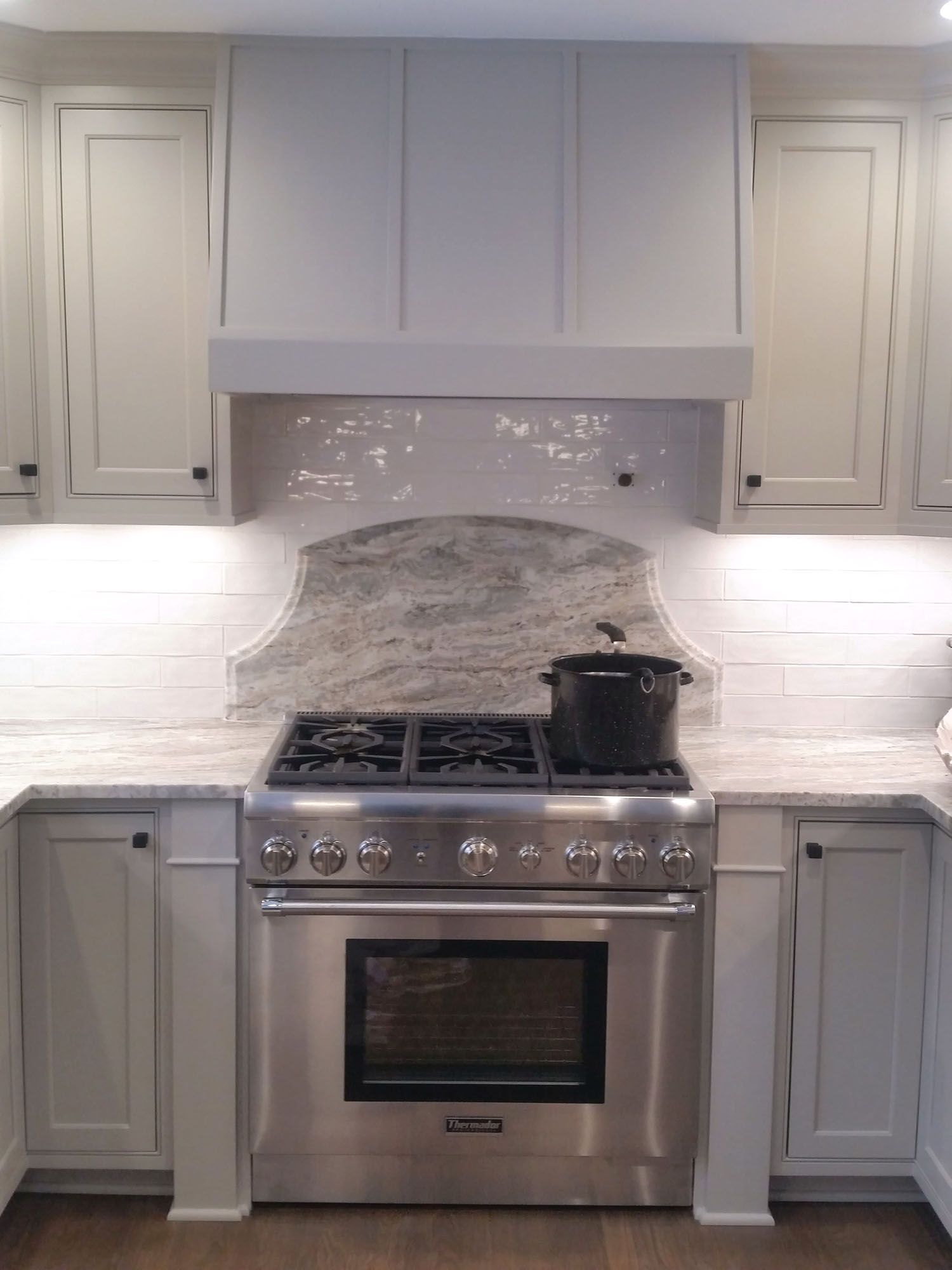 a stainless steel stove top oven is sitting in a kitchen with white cabinets .