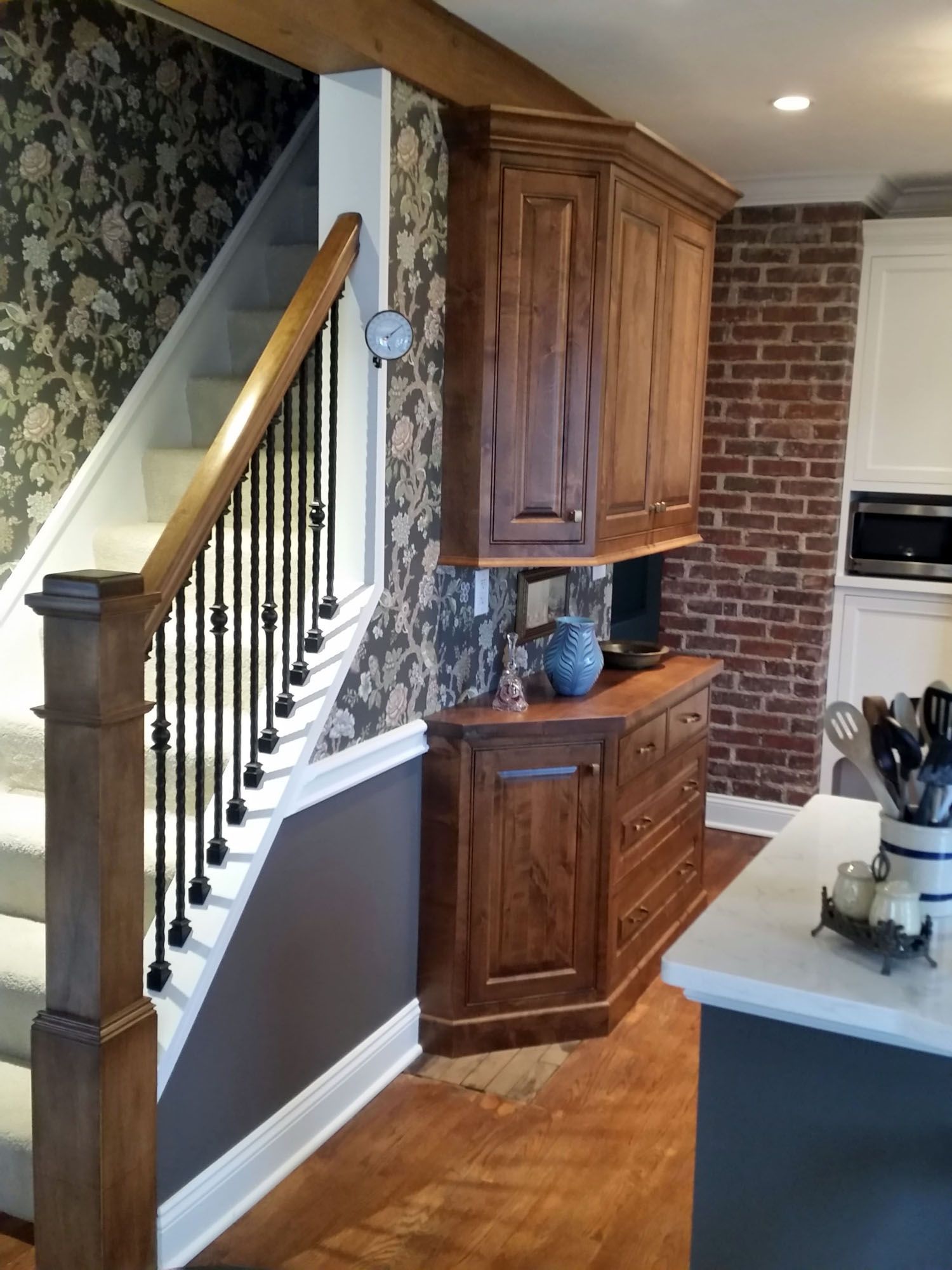 a kitchen with a staircase and a brick wall Amish Cabinets.
