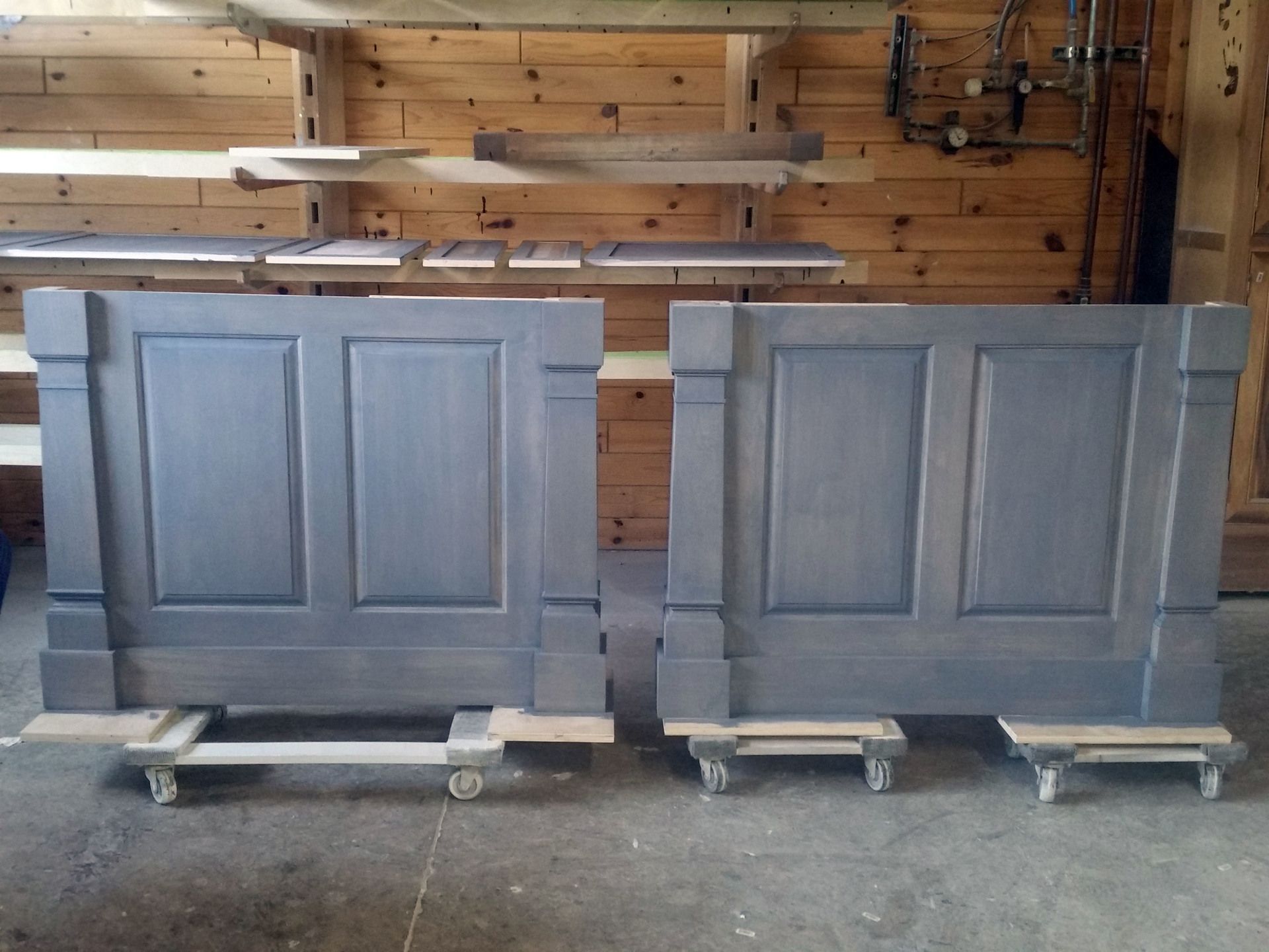 two pieces of wood are sitting on wheels in front of a wooden wall