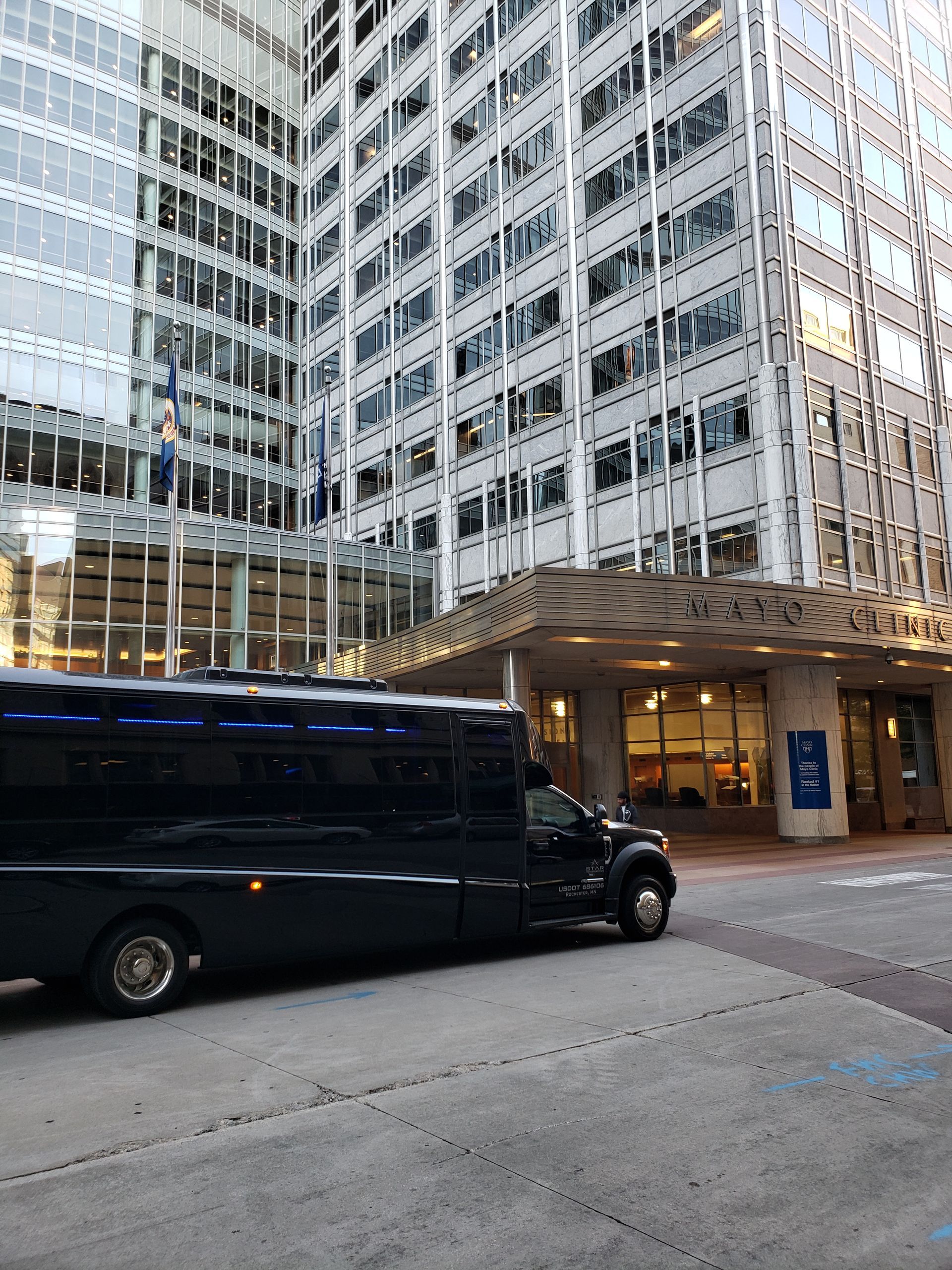 Black shuttle bus parked in front of a modern, glass-paneled building.
