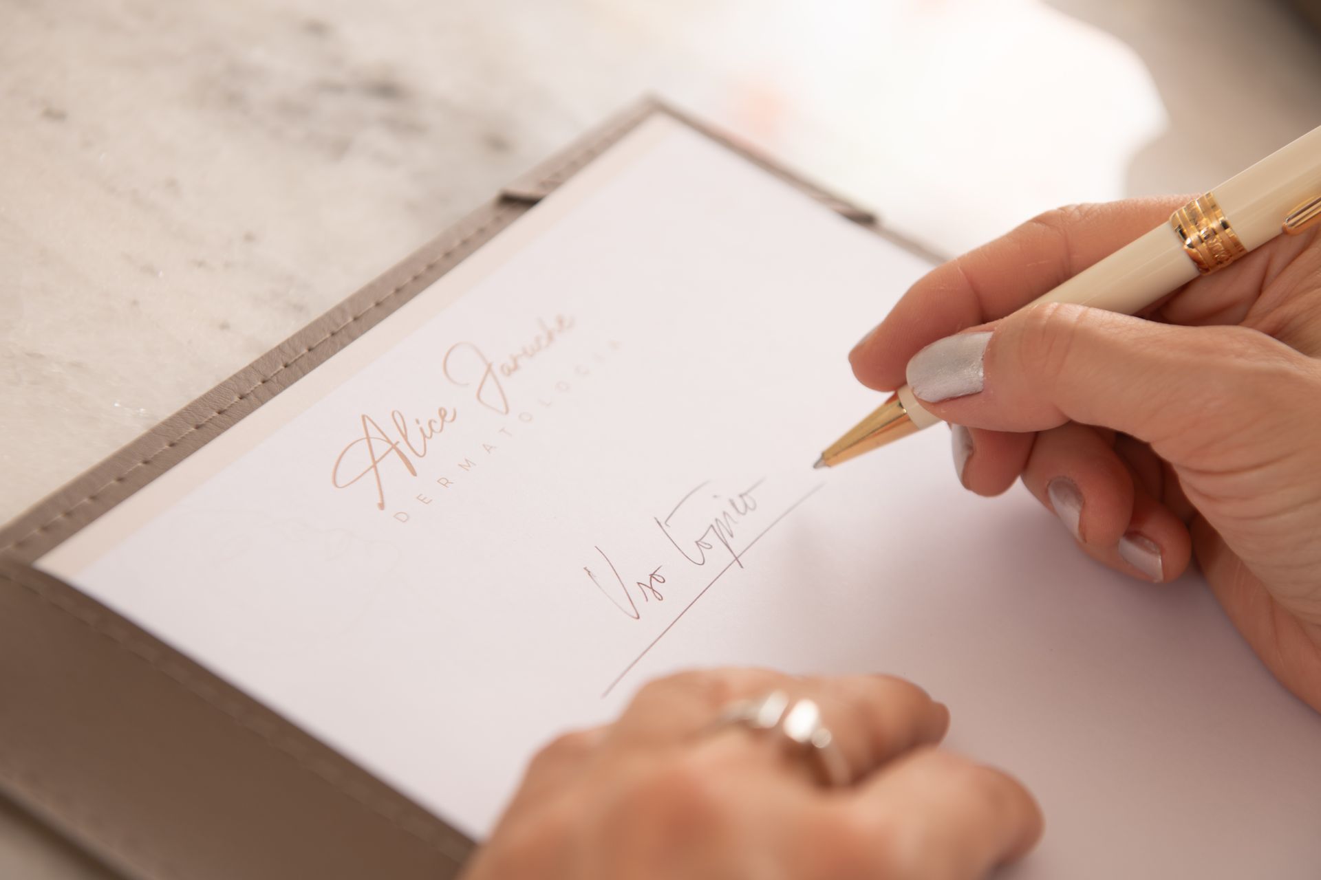 Uma mulher está escrevendo em um pedaço de papel com uma caneta.
