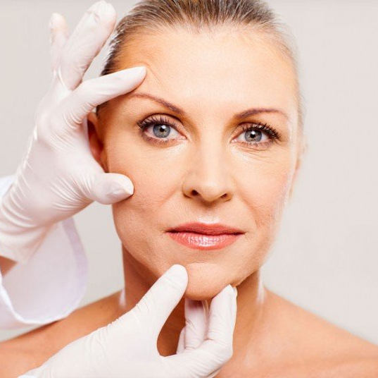 O rosto de uma mulher está sendo examinado por um médico usando luvas brancas.