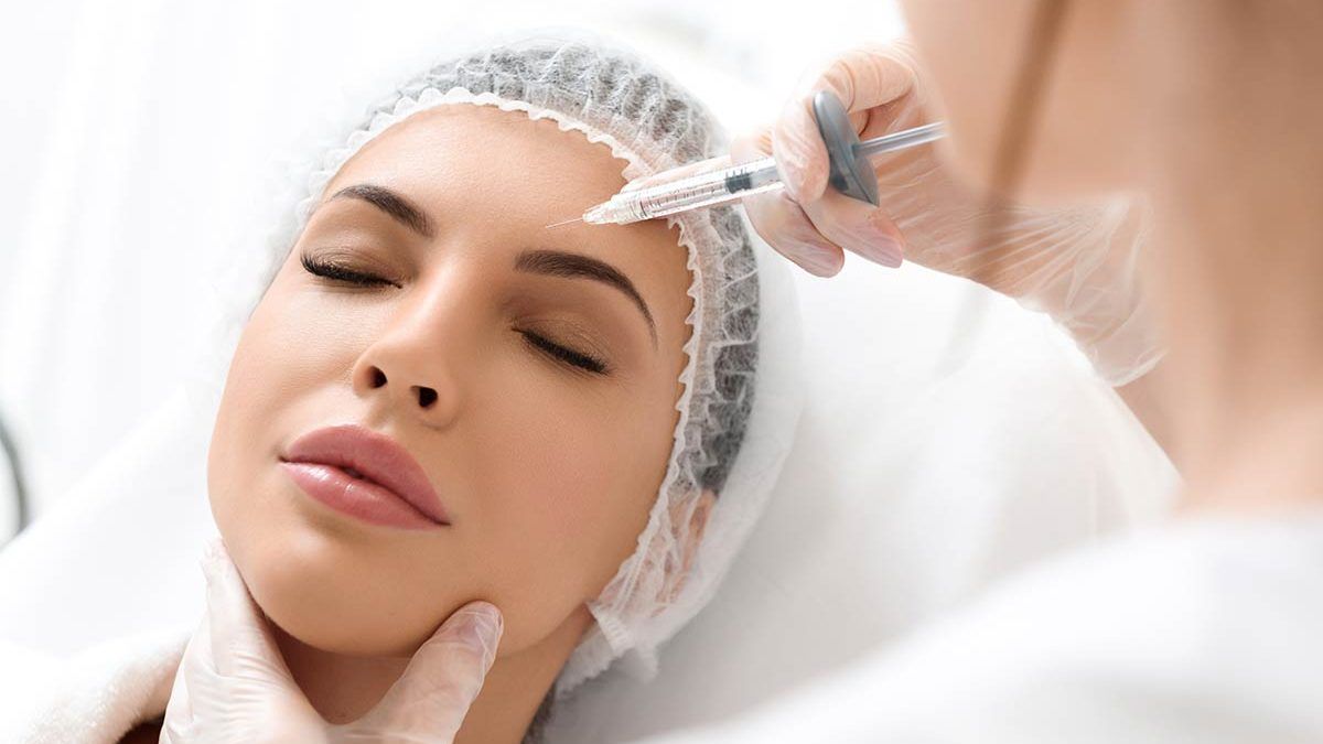 Uma mulher está recebendo uma injeção de botox na testa.