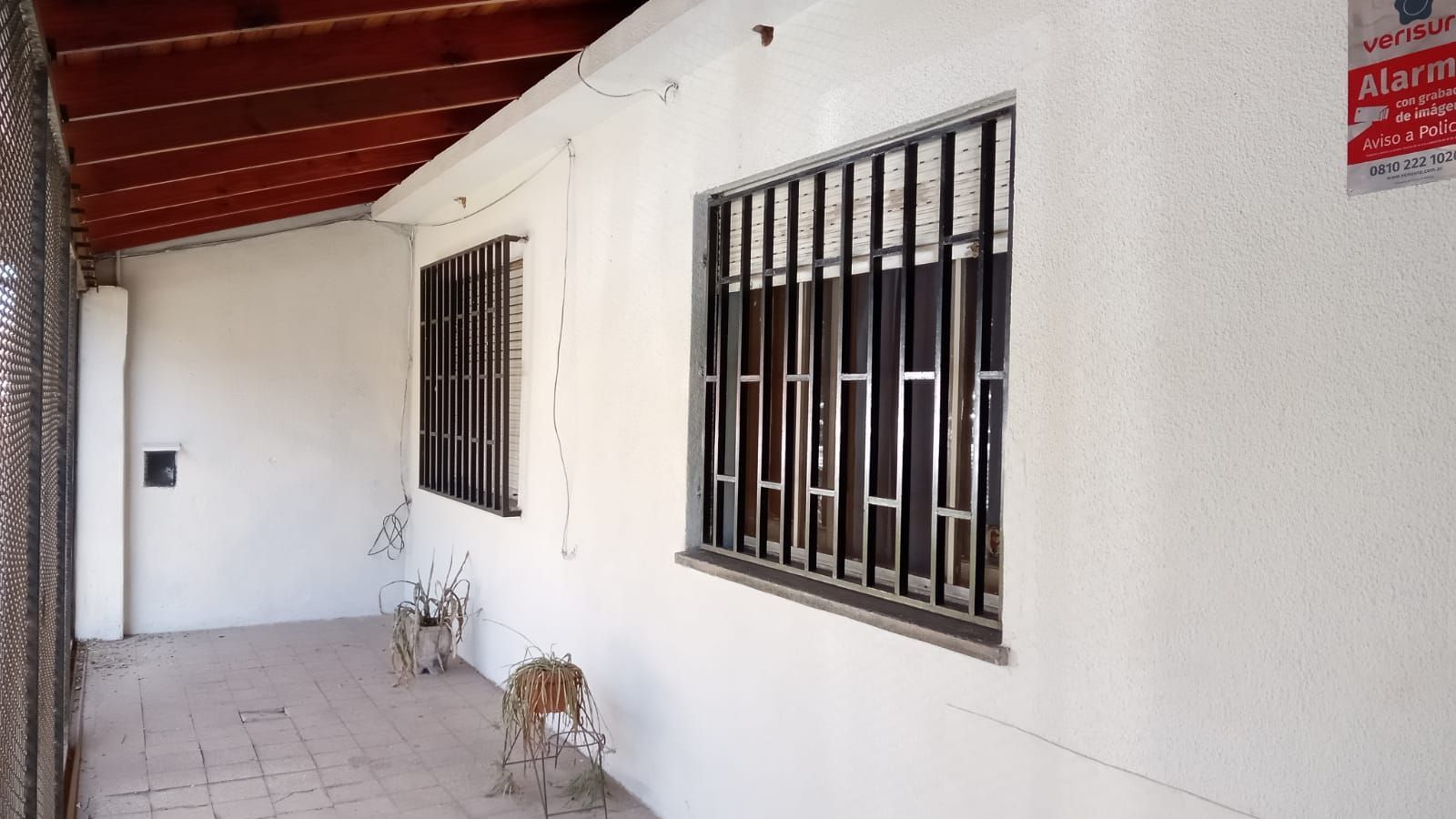 Exterior de edificio blanco con ventanas enrejadas y techo de madera.