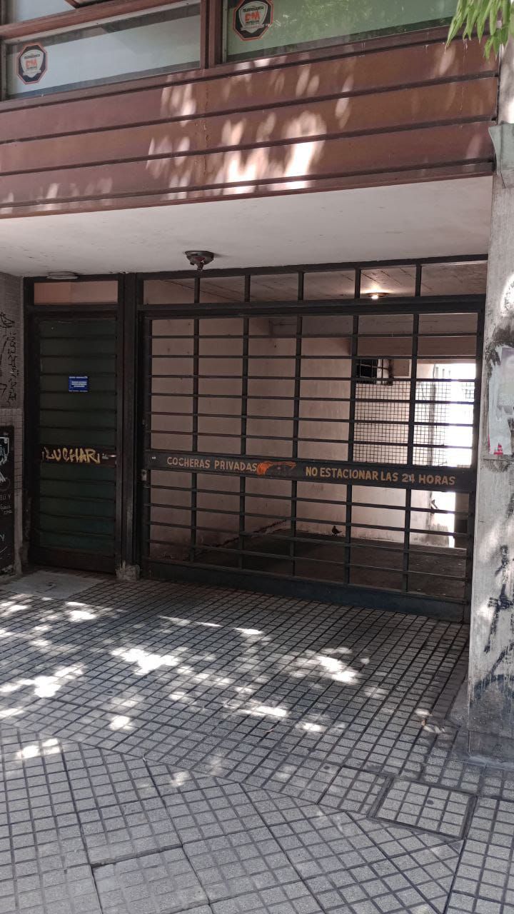Entrada al edificio con portón metálico de seguridad y pasarela de baldosas.