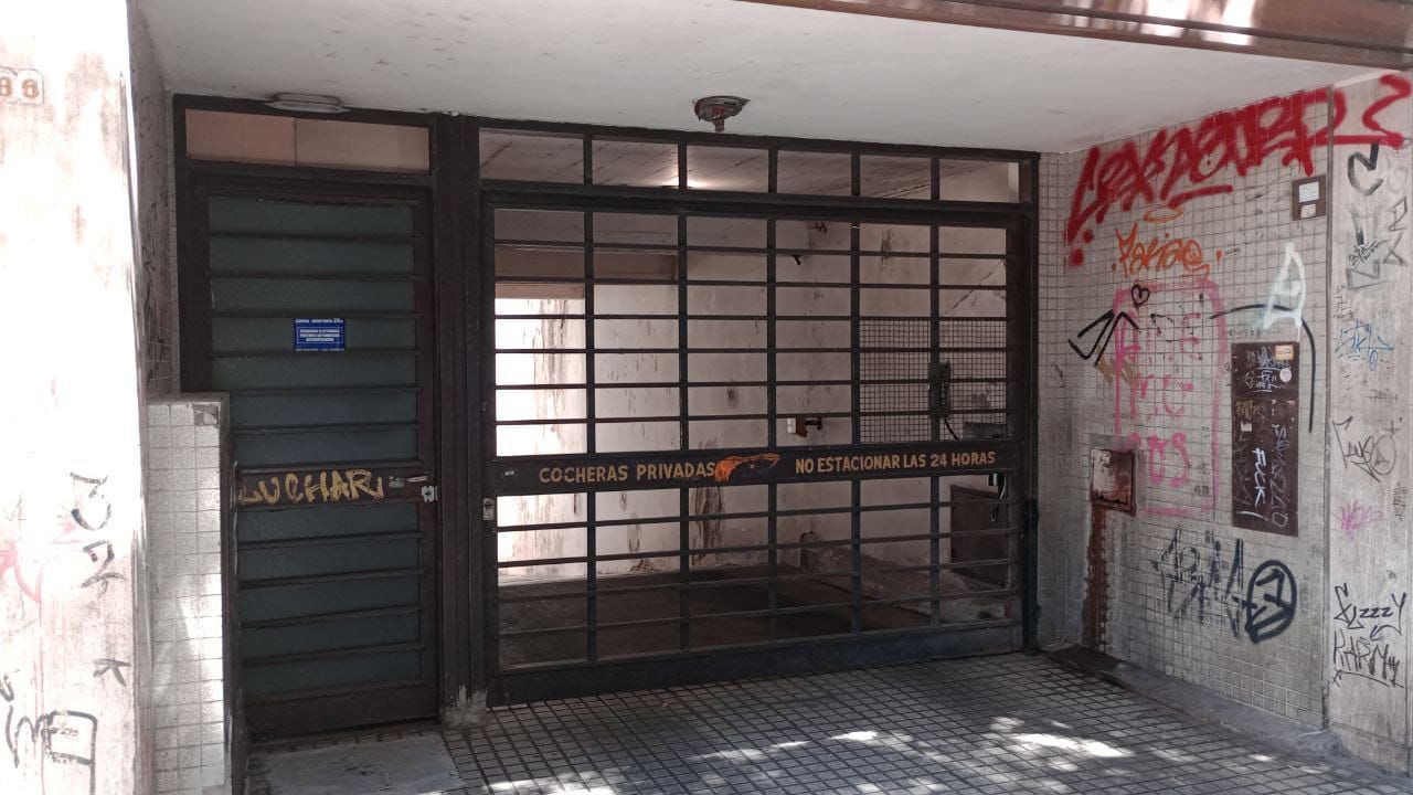 Entrada al edificio con portón metálico de seguridad y pasarela de baldosas.