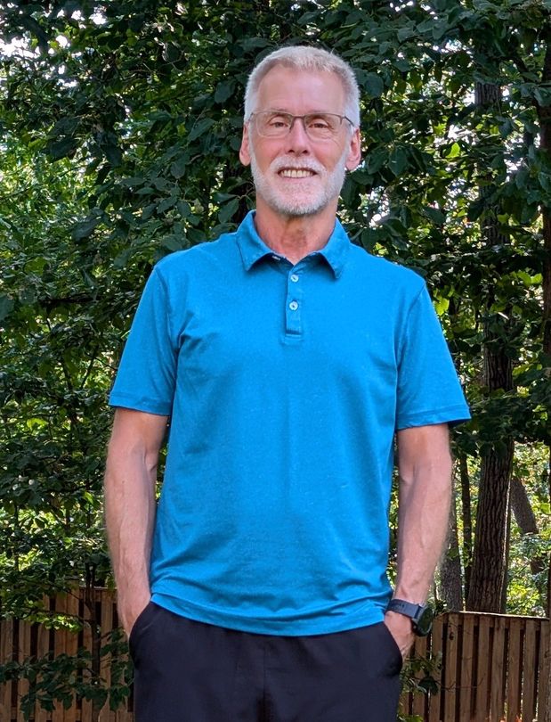 A man with a backpack is walking up a grassy hill.
