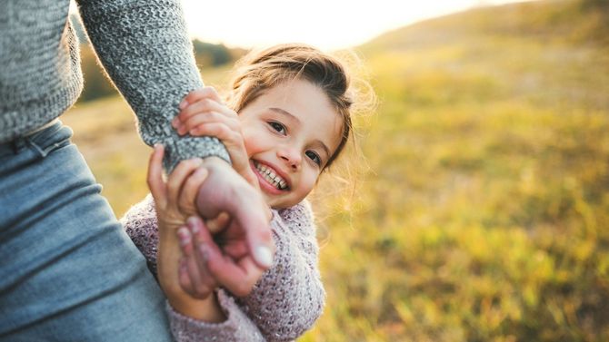 A woman is holding a little girl in her arms in a field.