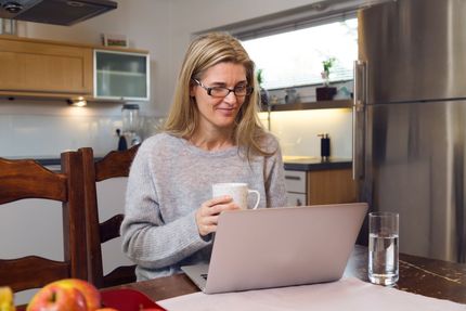 A woman is sitting at a table using a laptop computer.