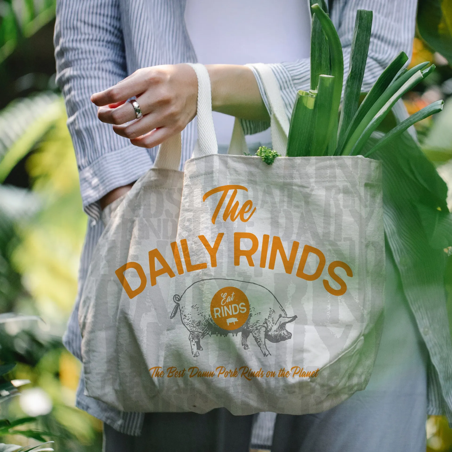 A woman is holding a tote bag that says the daily rinds