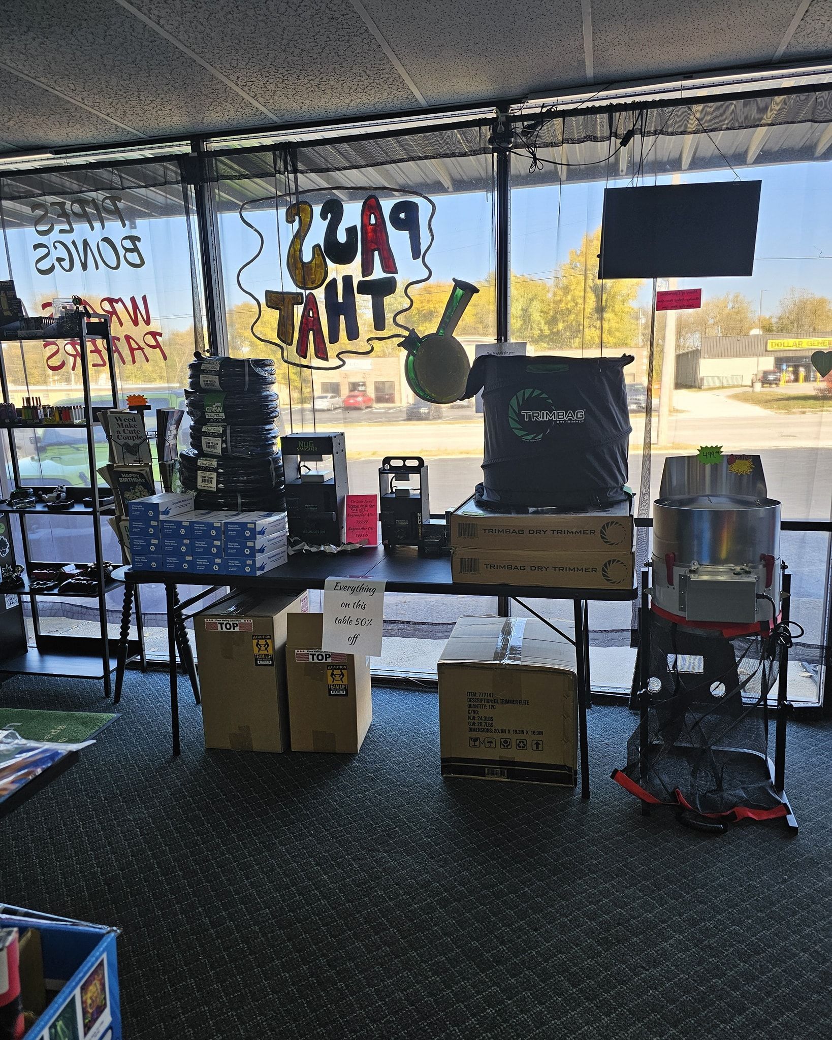 Interior of a store, displaying various products on tables near a window.