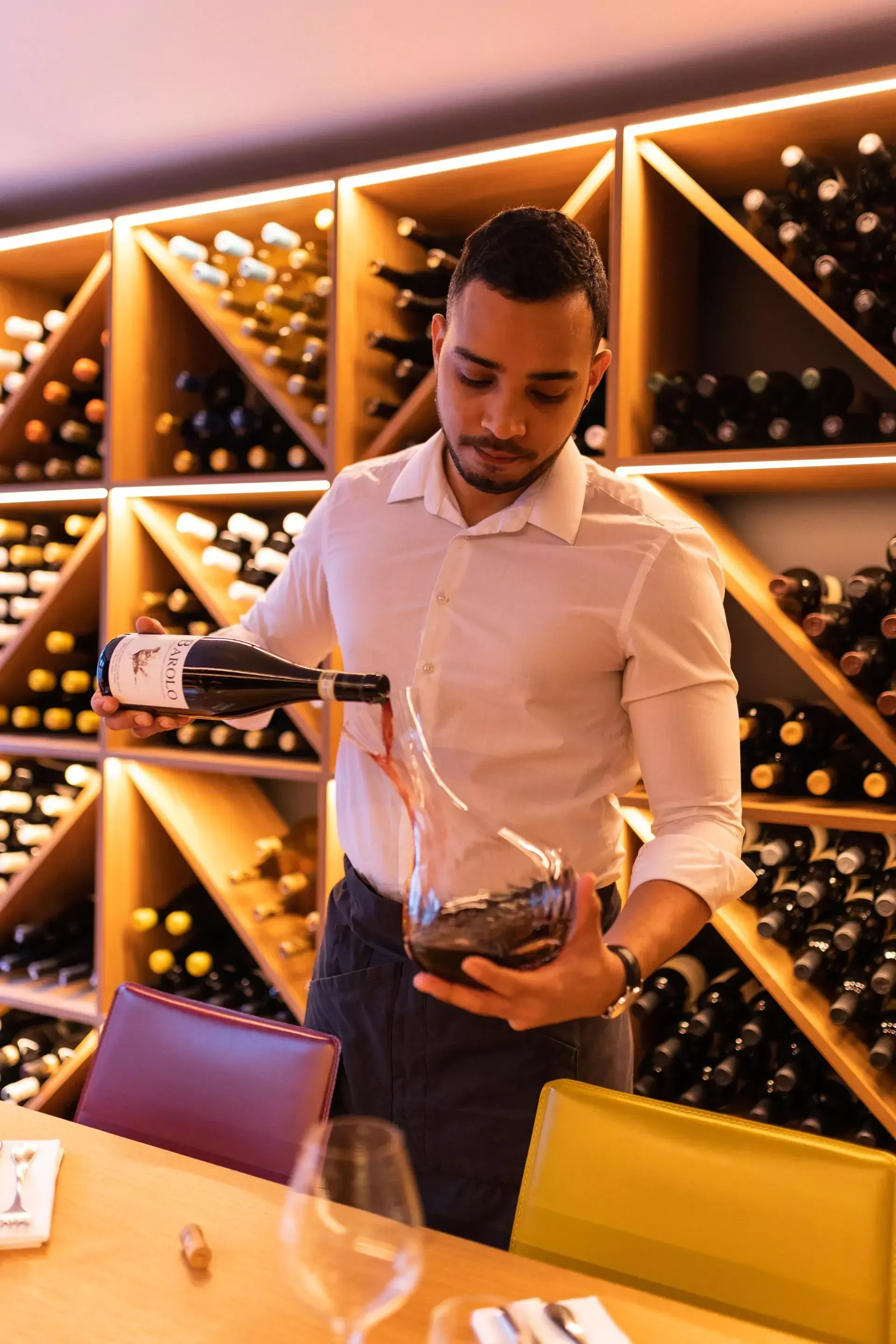 Un homme verse du vin dans un verre dans une cave à vin.
