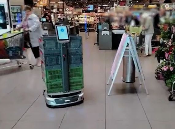 Robot shopping cart with a screen in a grocery store.