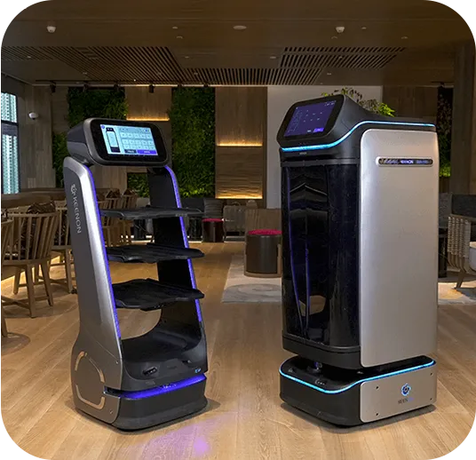 Two service robots in a restaurant. One with shelves, the other a closed box, both with screens.