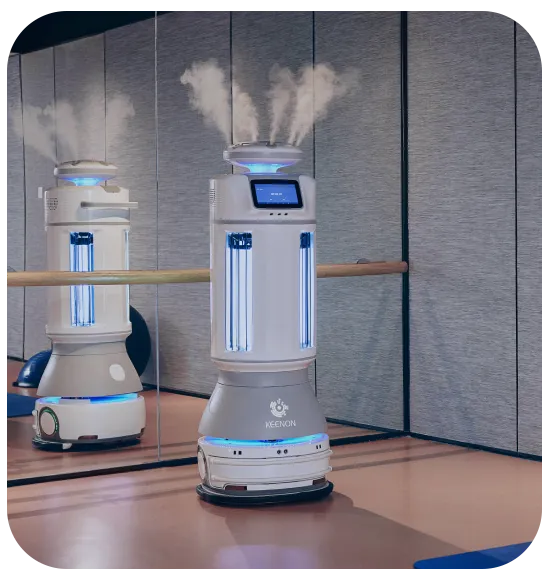 Two disinfection robots emitting mist, in a dance studio with a ballet barre and mirror.