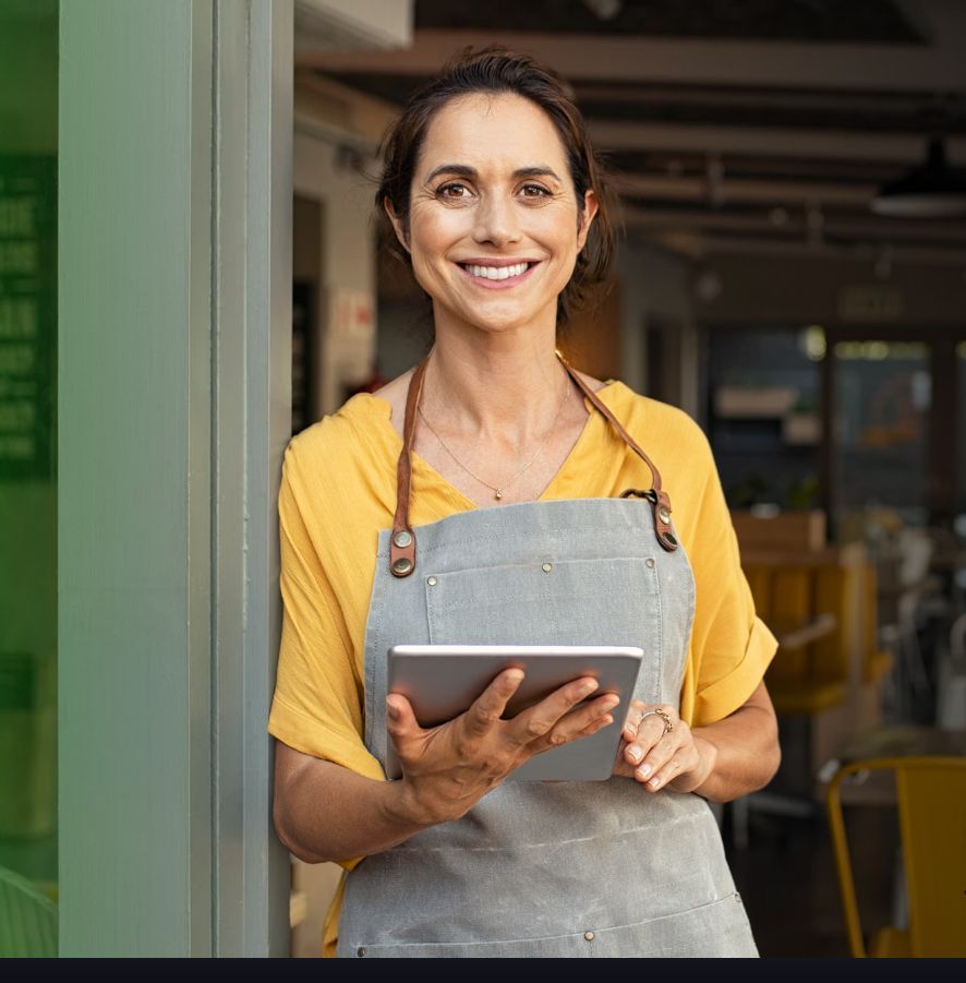 Two businesspeople shaking hands over a table with papers and charts.