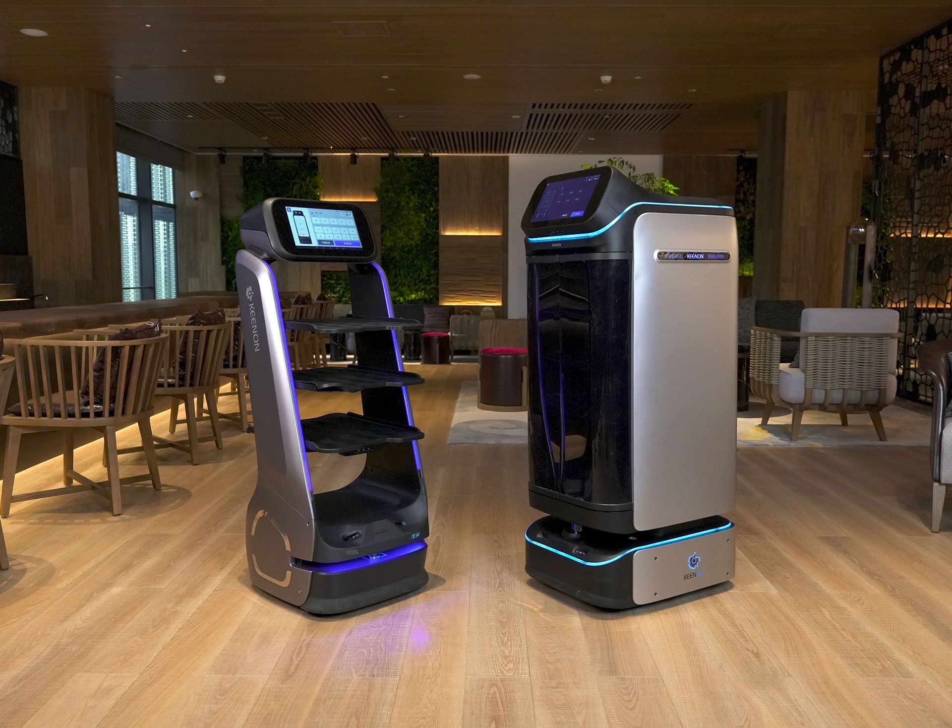 Two robotic servers in a restaurant. One with shelves, the other enclosed.