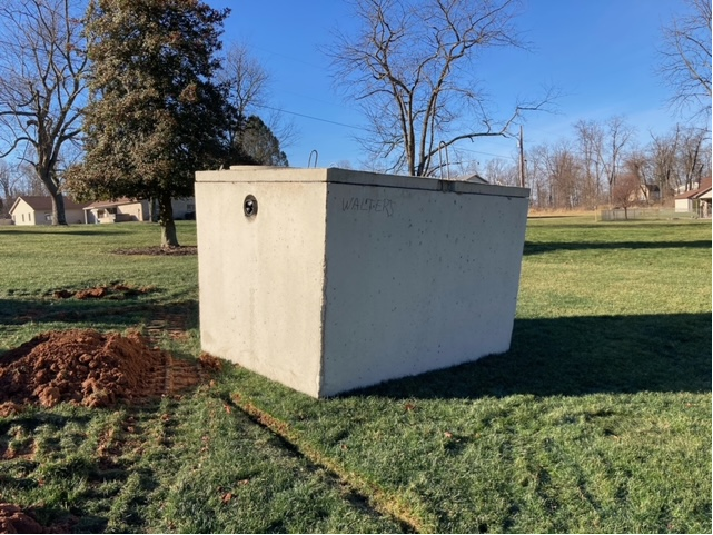 A large concrete block is sitting in the middle of a grassy field.