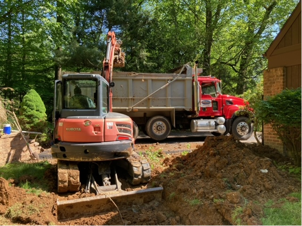 A red dump truck is parked next to a small excavator.