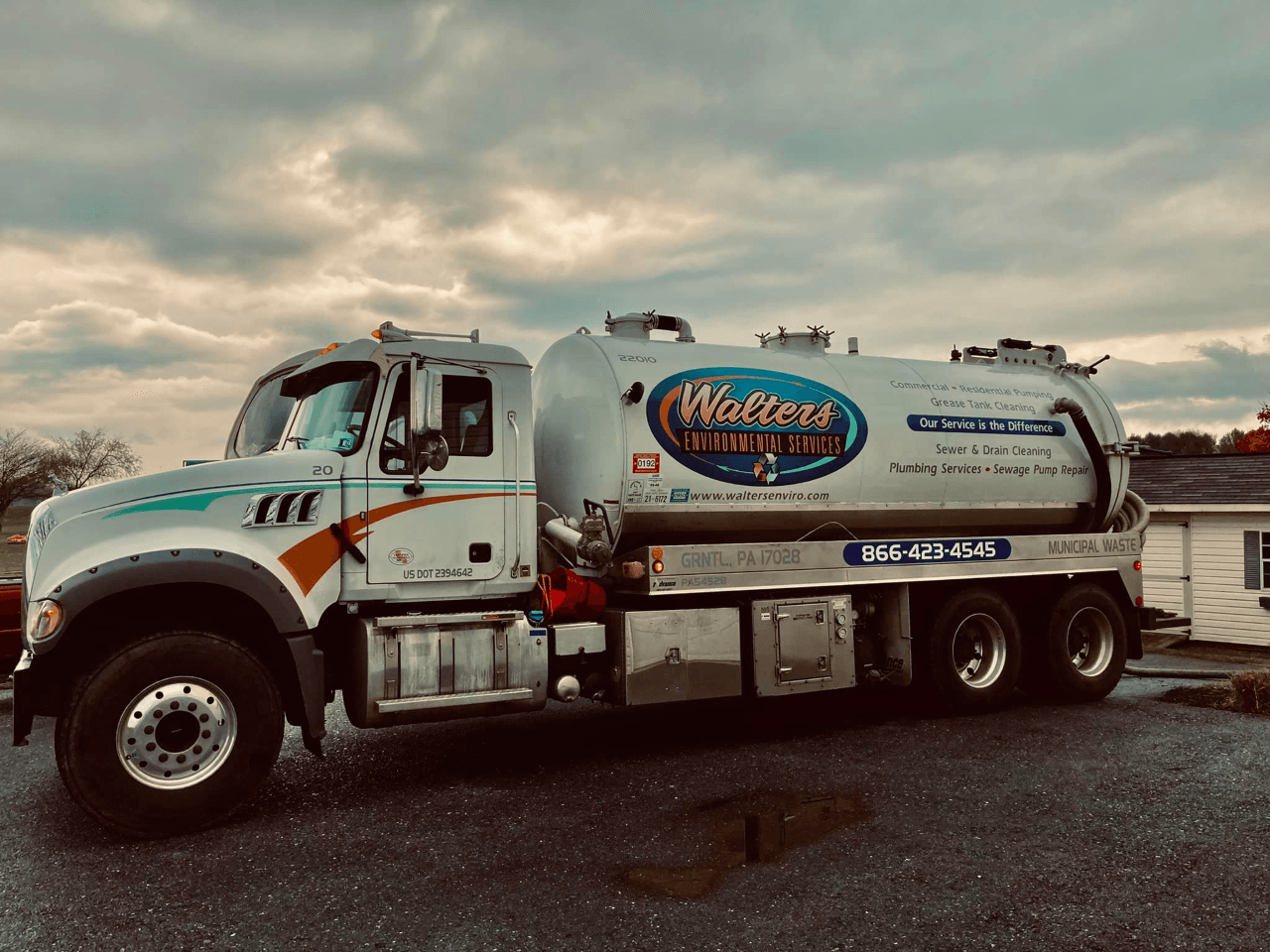 A septic tank truck is parked in front of a house.
