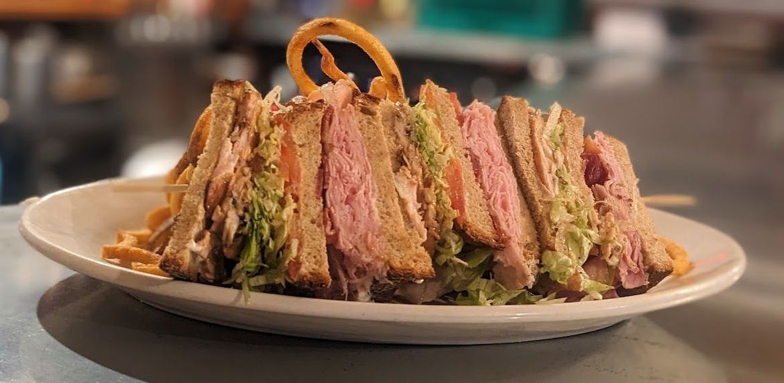 A sandwich with meat and lettuce on a plate on a table.