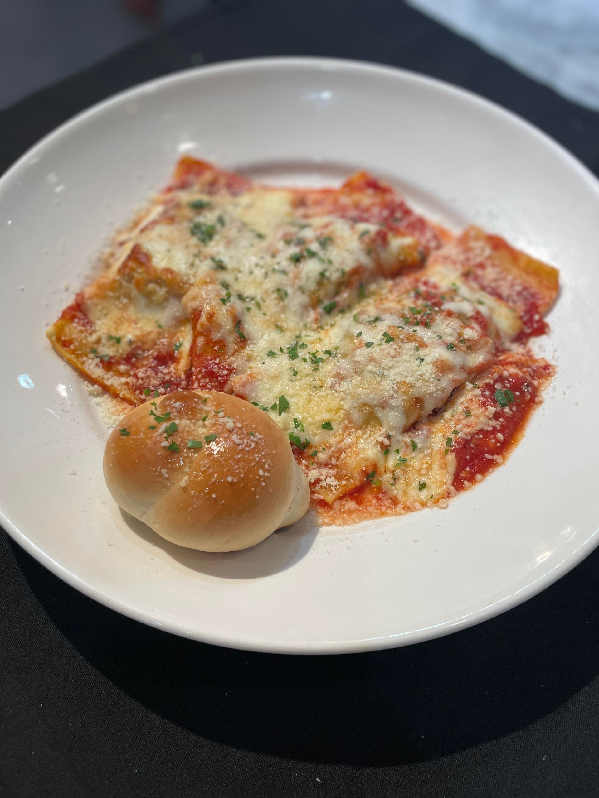 A white plate topped with a slice of lasagna and garlic bread.