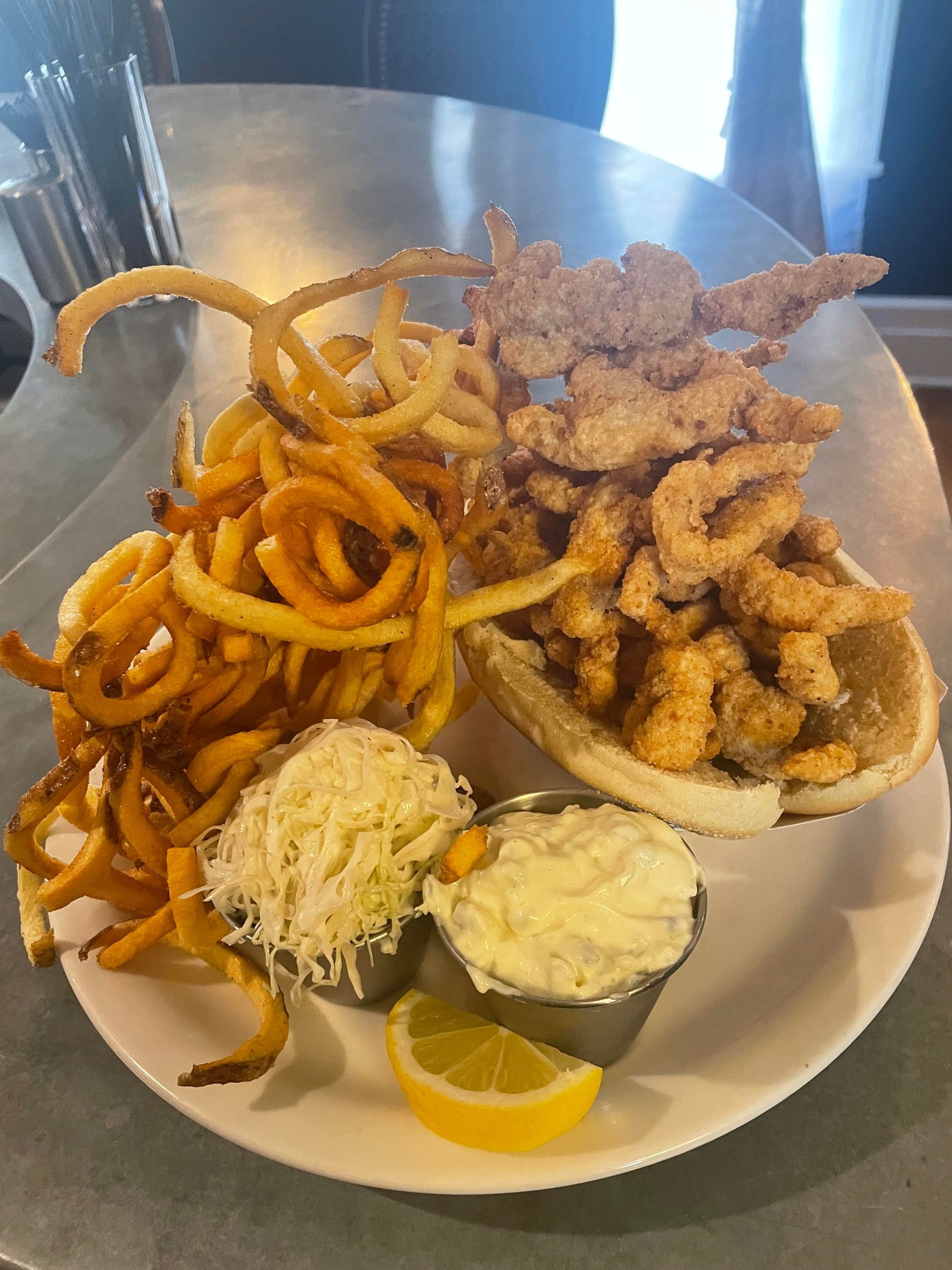 A plate of food with shrimp , french fries , and coleslaw on a table.