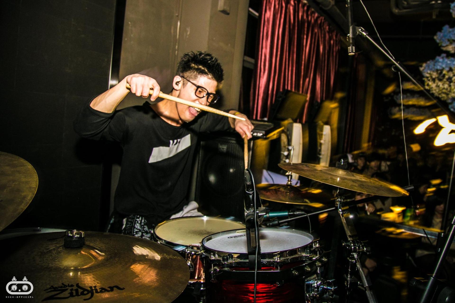 A man is playing drums in a dark room.