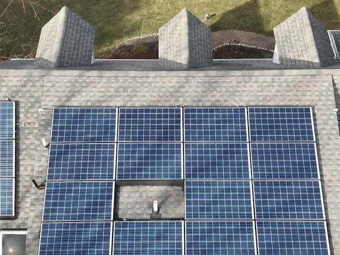 Overhead view of a rooftop with solar panels and small, gray, pointed roof structures.