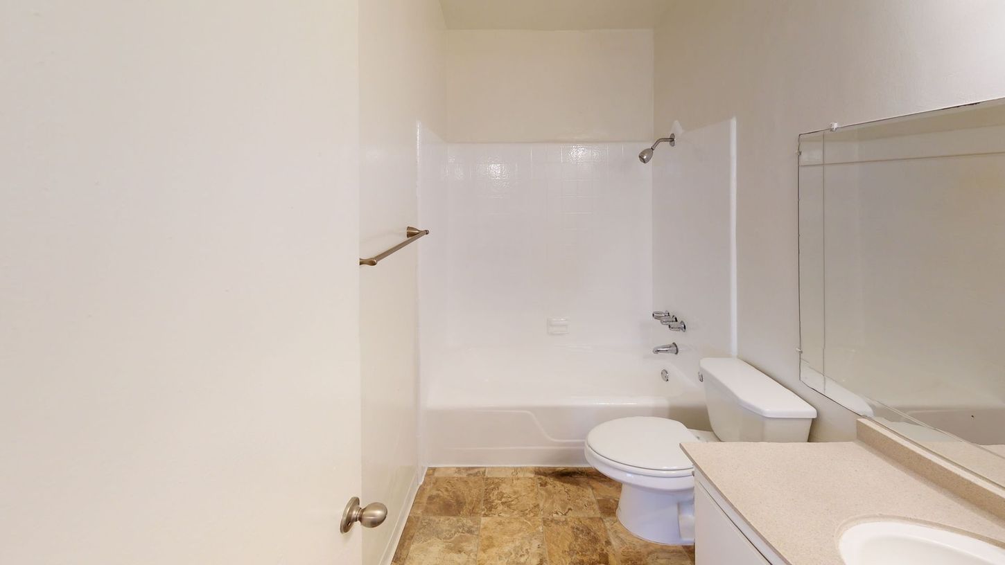 Bathroom with white fixtures, beige floor, and a closed door.