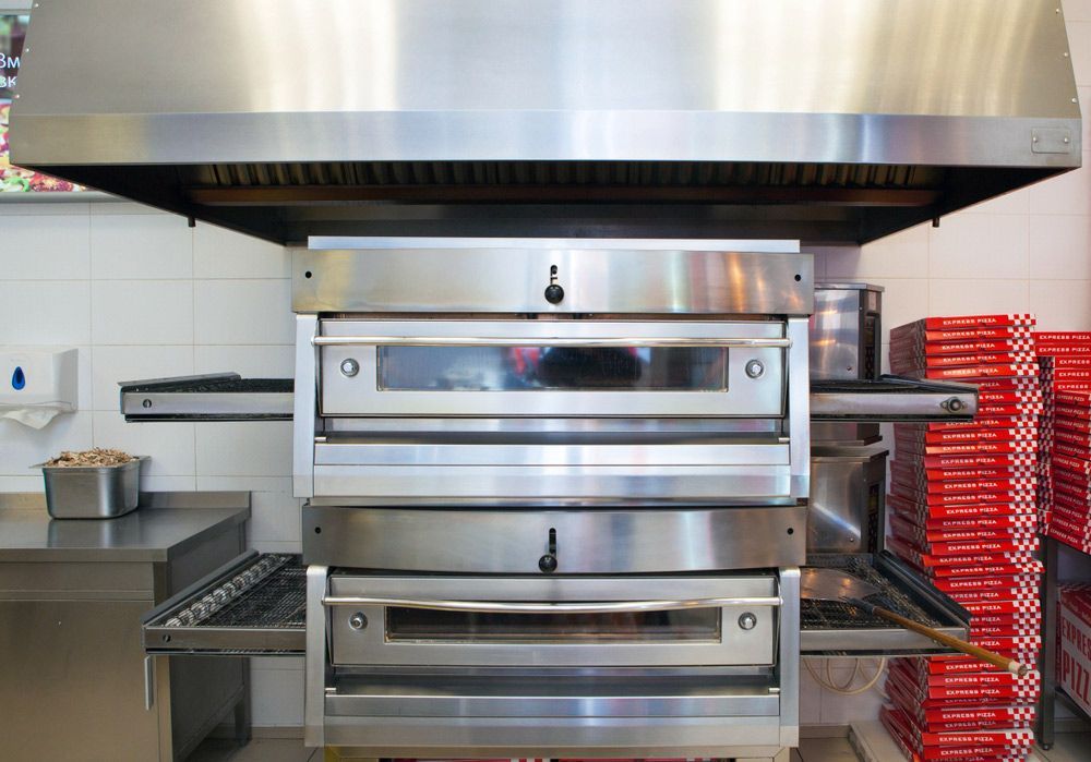 A Stainless Steel Oven Is Installed in A Kitchen Next To A Stack Of Pizza Boxes — Appliance City in Port Macquarie, NSW