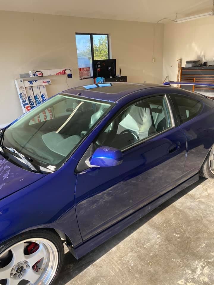 Blue coupe car parked in a garage with red brake calipers, a rear spoiler, and silver wheels.