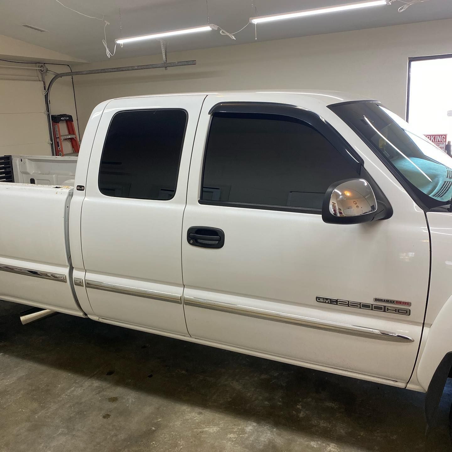 White pickup truck with tinted windows parked inside a garage.