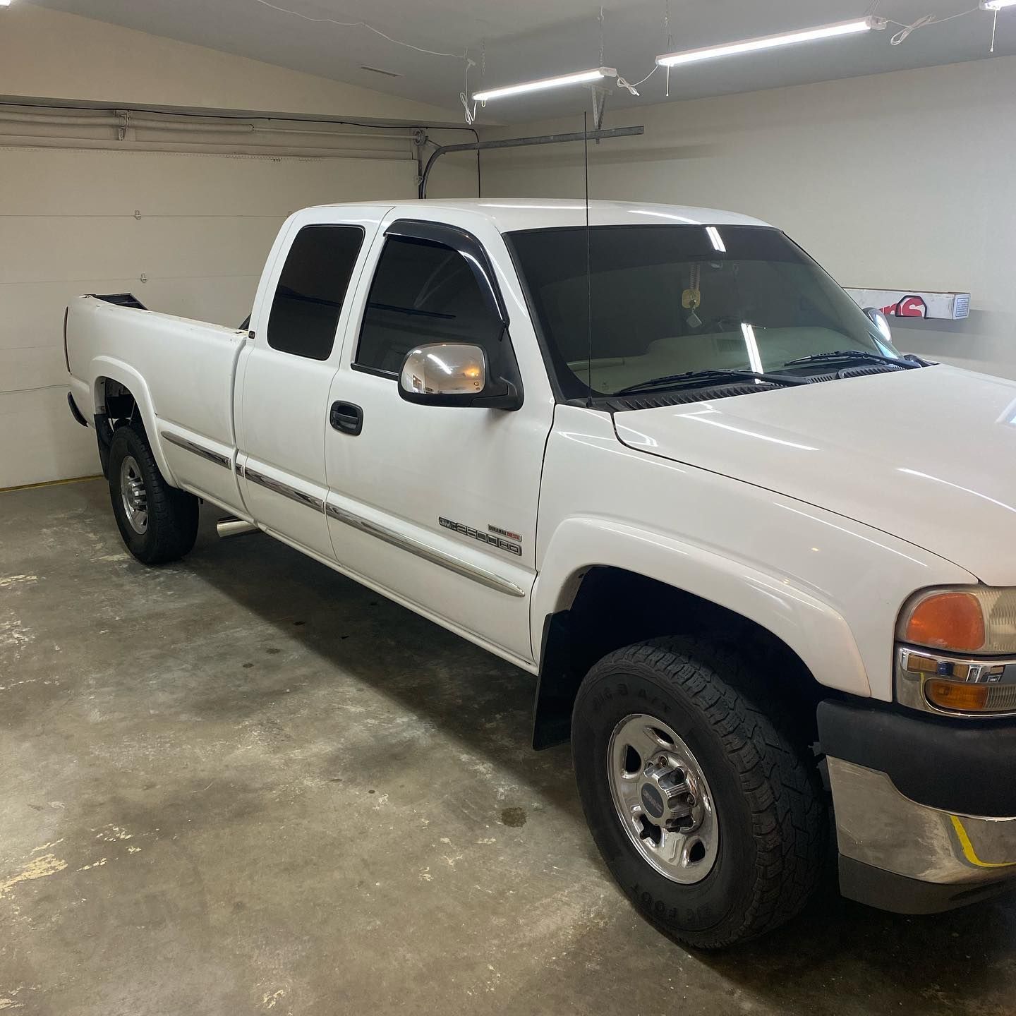 White Chevy Silverado pickup truck parked inside a garage. It has tinted windows and chrome details.