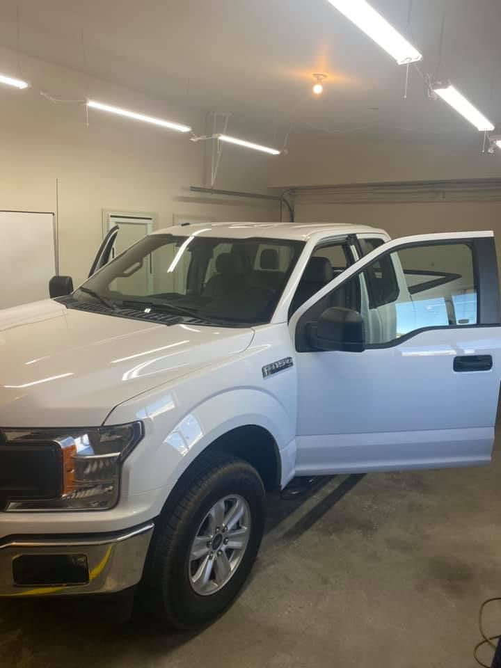 White Ford pickup truck with doors open inside a garage.