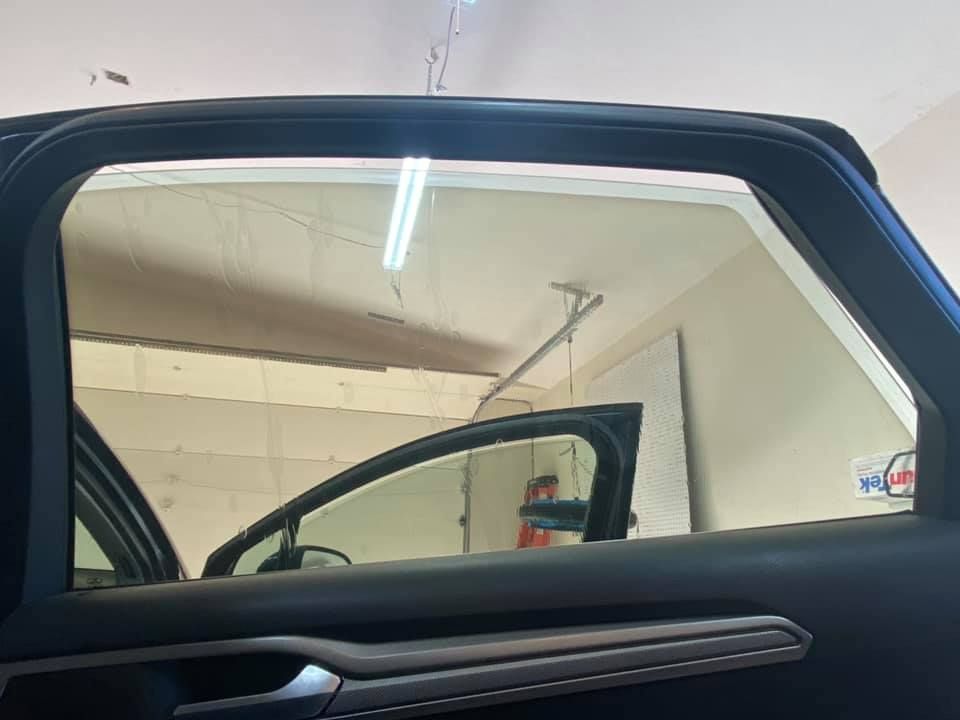 Inside view of a car with the front passenger window open, the door open, and the garage visible through the window.
