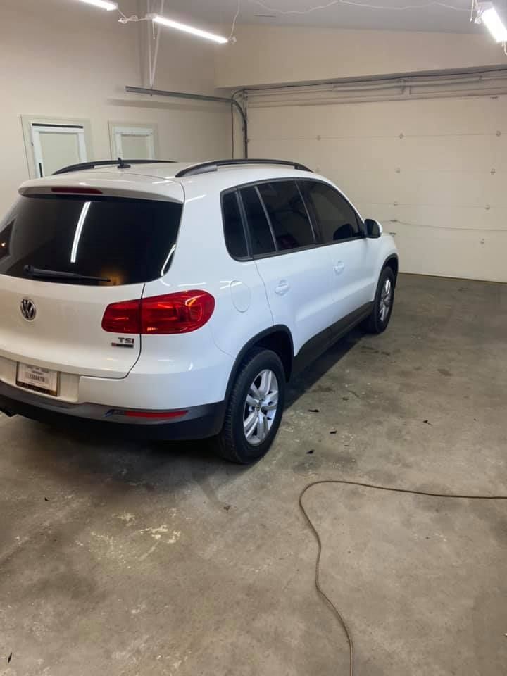 White Volkswagen Tiguan SUV in a garage, with tinted windows and a reflective floor.