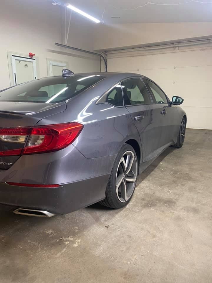 A gray Honda Accord sedan parked inside a garage. The car is facing towards the right with taillights and a rear bumper visible.