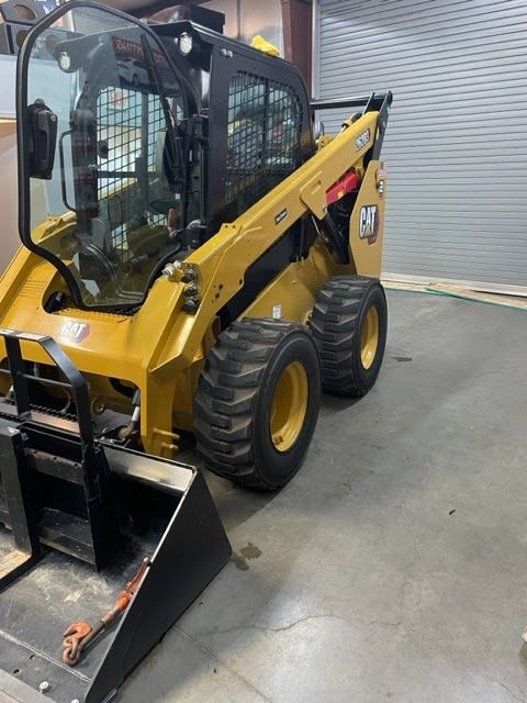 Yellow Caterpillar skid steer loader parked inside a garage.