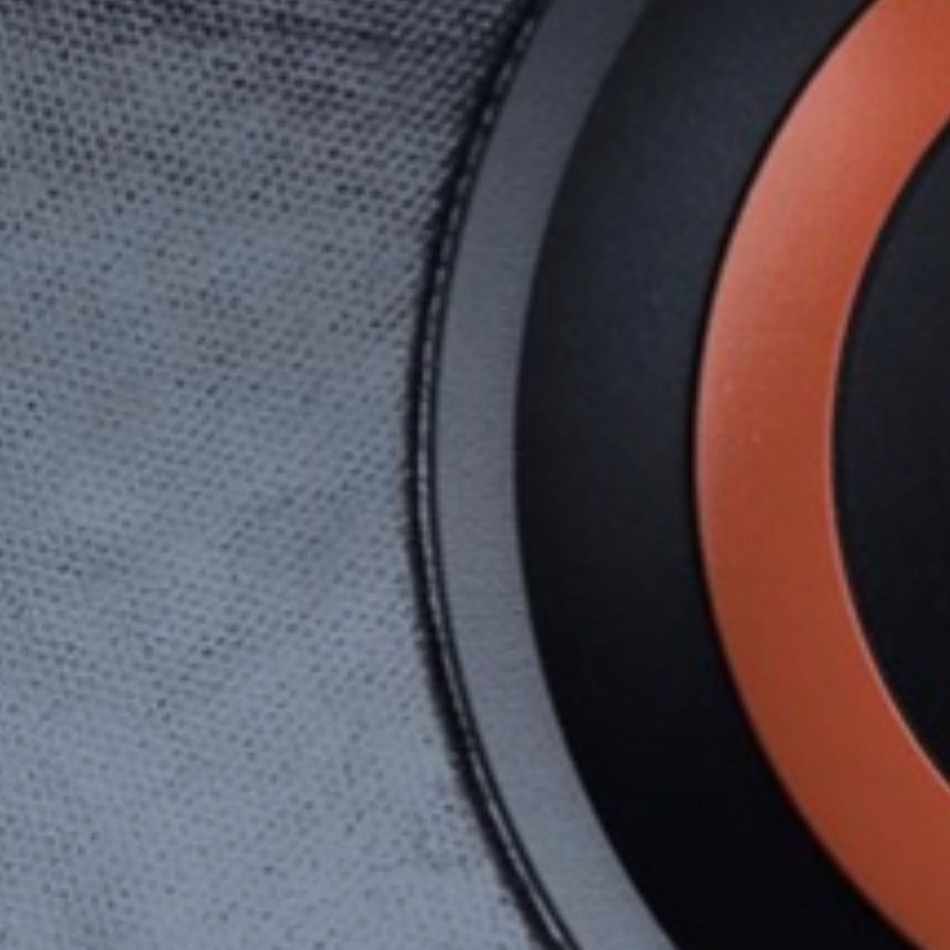 Close-up of textured gray leather, with a black and orange circular design to the right.