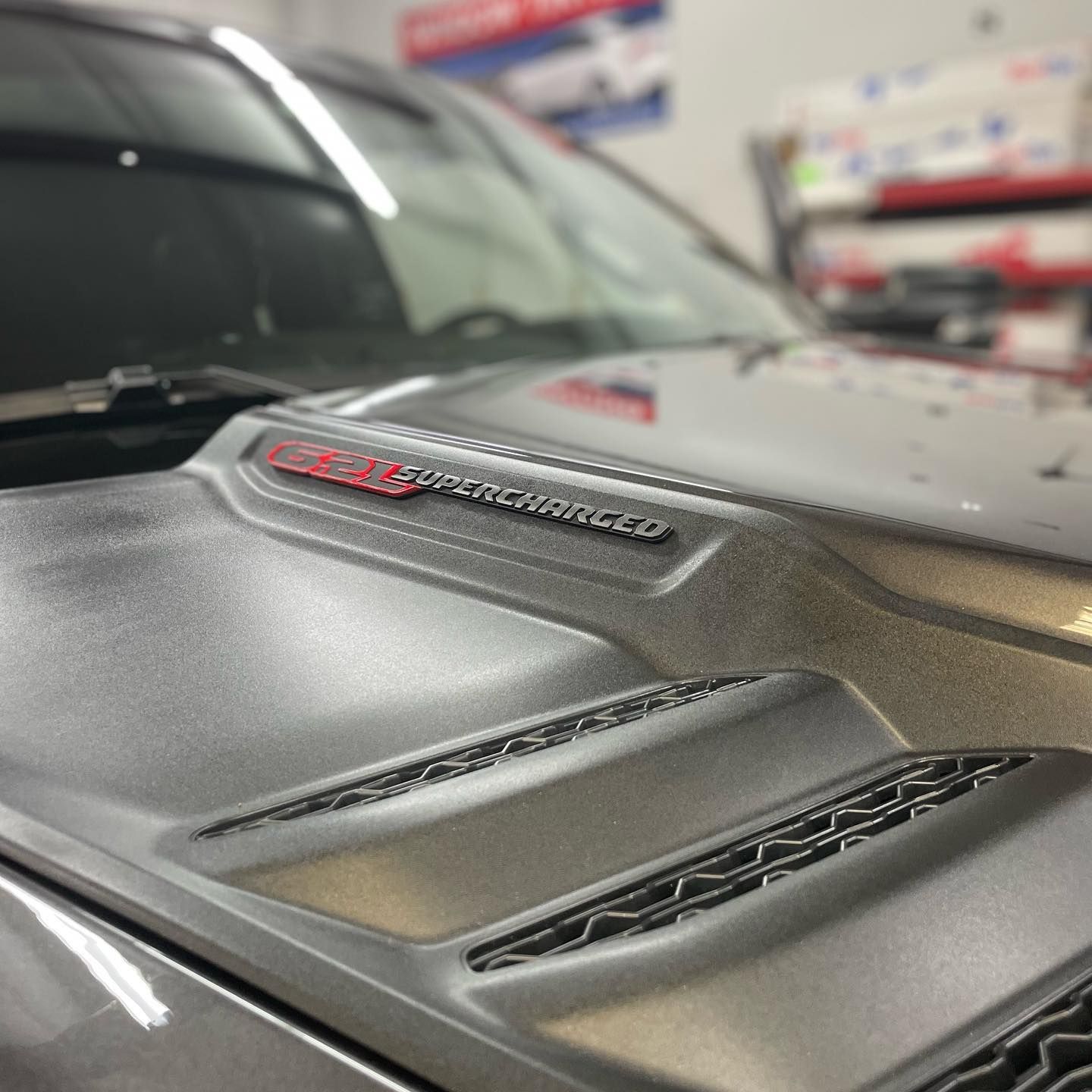 Close-up of a gray car hood with air vents and a red 