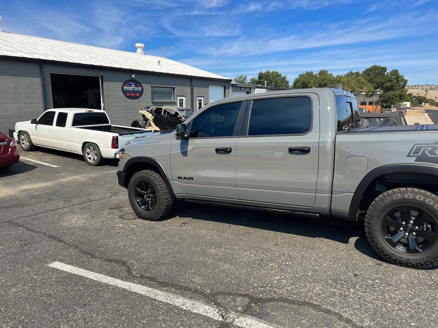 Gray Ram pickup truck parked outside a building with other vehicles, on a sunny day. 